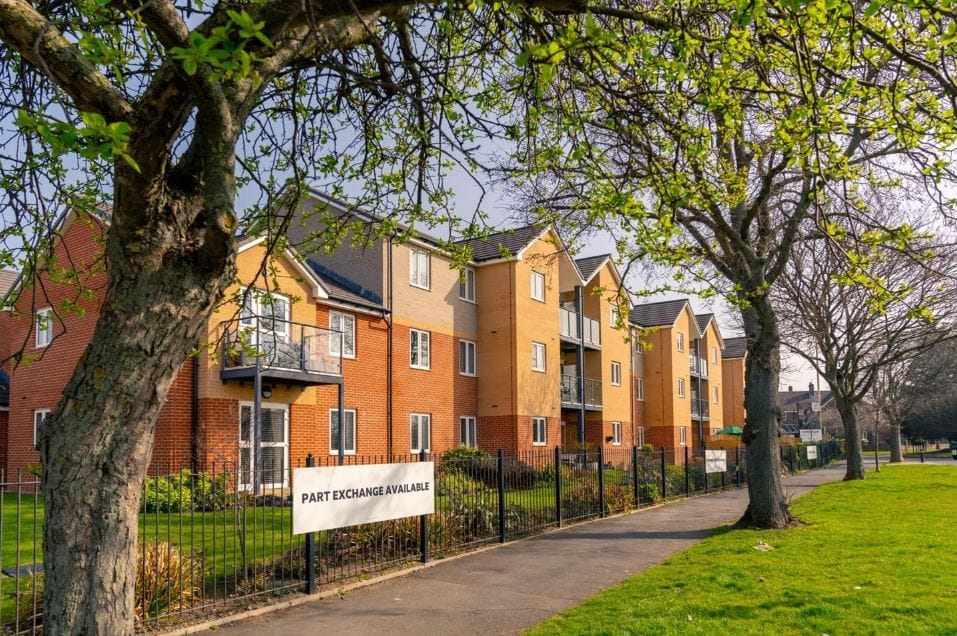 Exterior view of a senior living facility with trees and green lawn