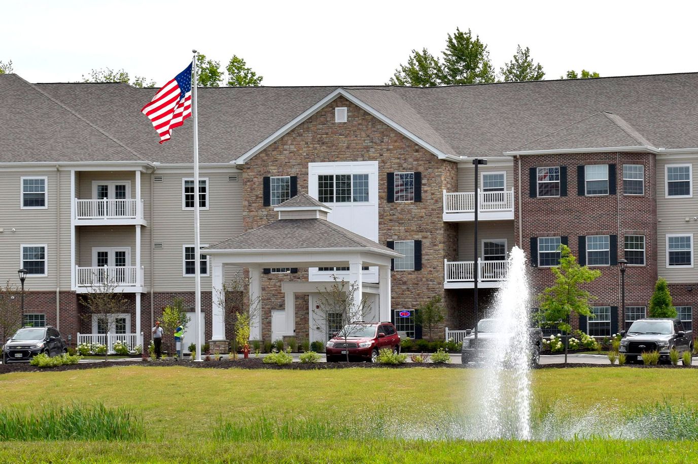 Exterior view of a senior living facility with flag and fountain