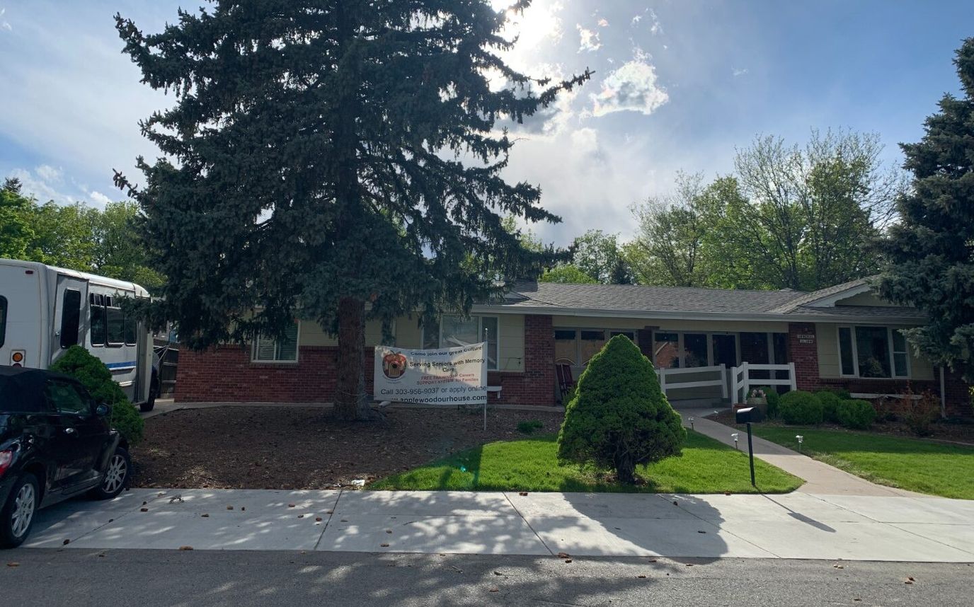 Exterior view of a nursing home with a banner and vehicle