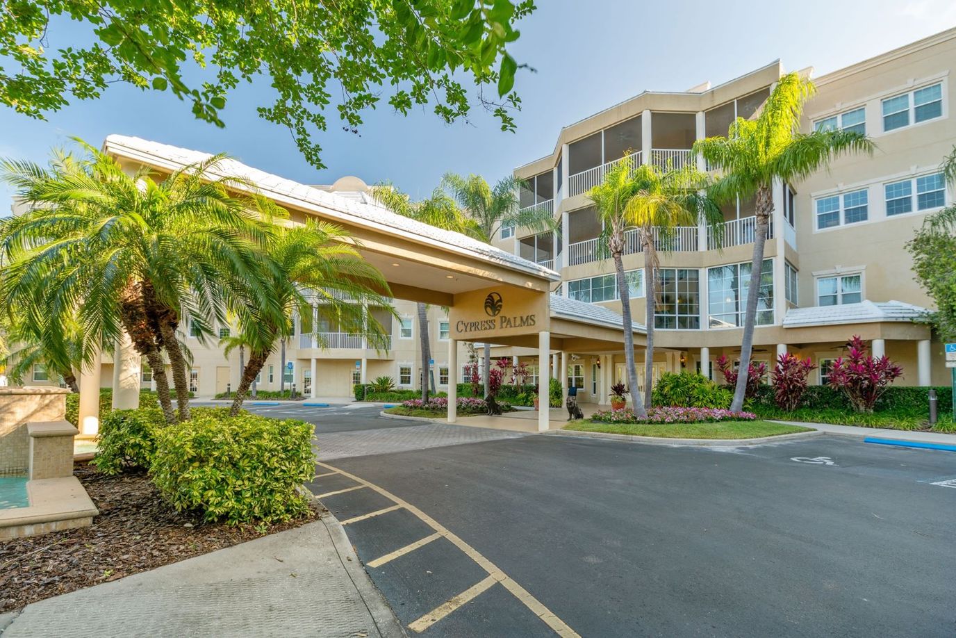 Entrance of Cypress Palms with palm trees and landscaping