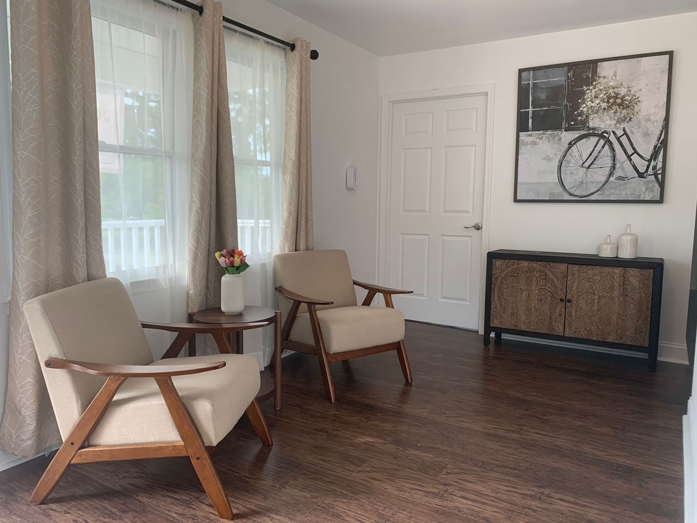 Cozy common area with two chairs and a bike painting