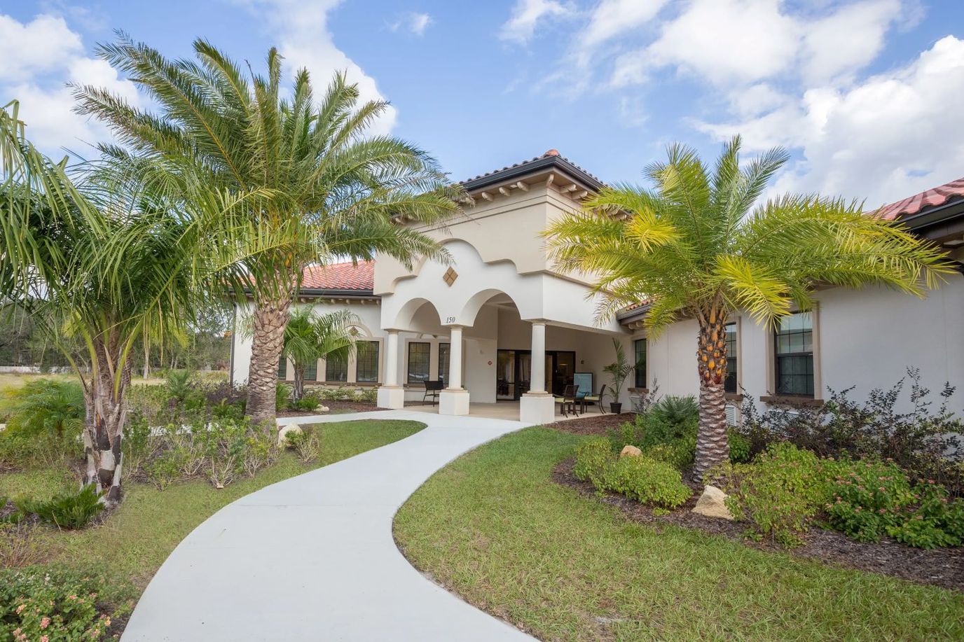 Exterior view of a senior living facility with palm trees