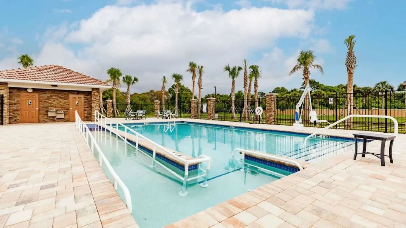 Pool area surrounded by palms and lounge chairs