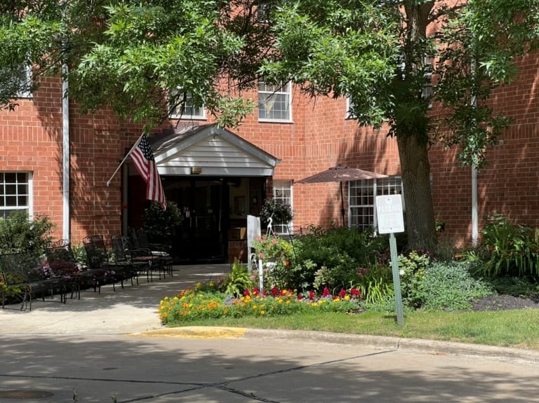 Exterior view of a senior living facility entrance with flowers