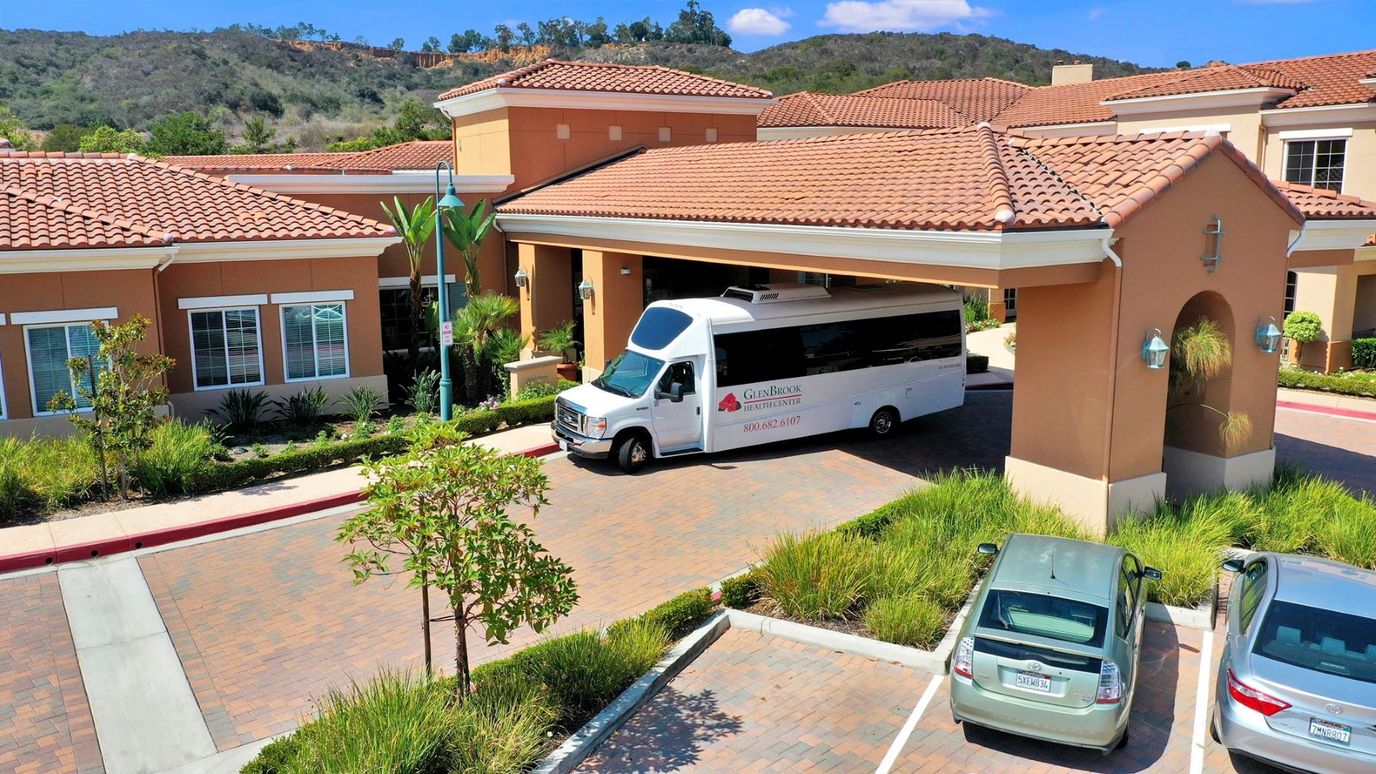 Exterior view of GlenBrook Health Center's entrance with shuttle bus