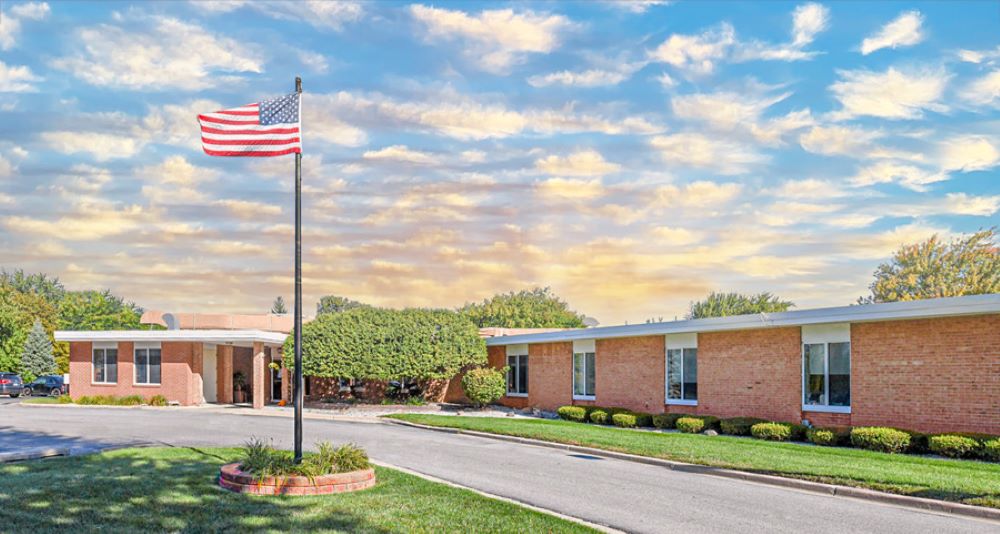 Exterior view of the nursing facility with flag and landscaping