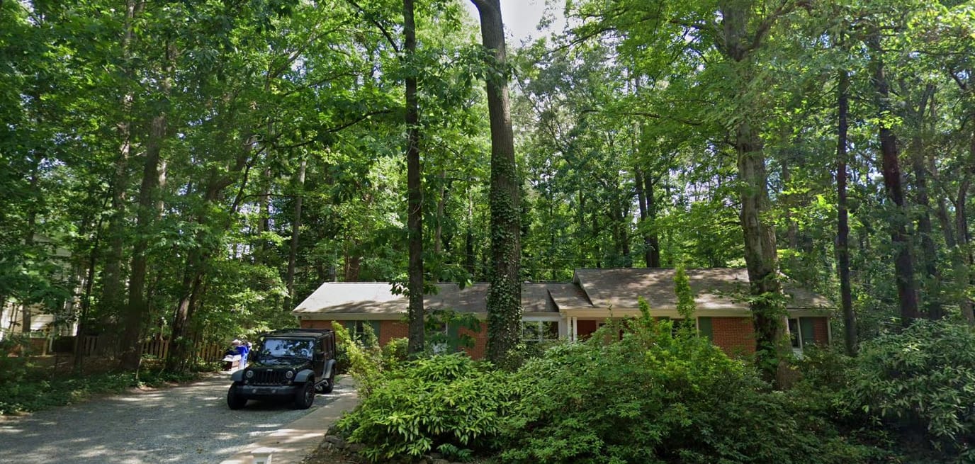 Front exterior view of a residential building surrounded by trees