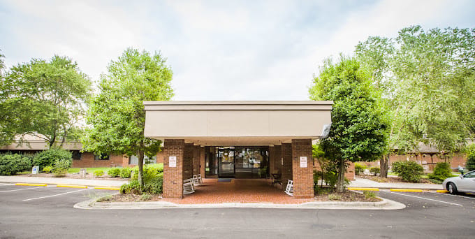 Exterior view of the facility entrance with trees and seating