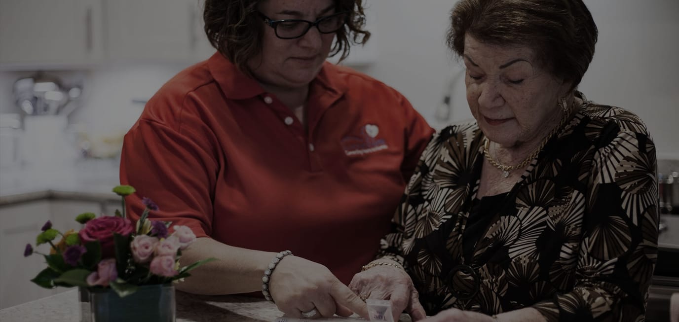 Caregiver assisting a senior resident at a table