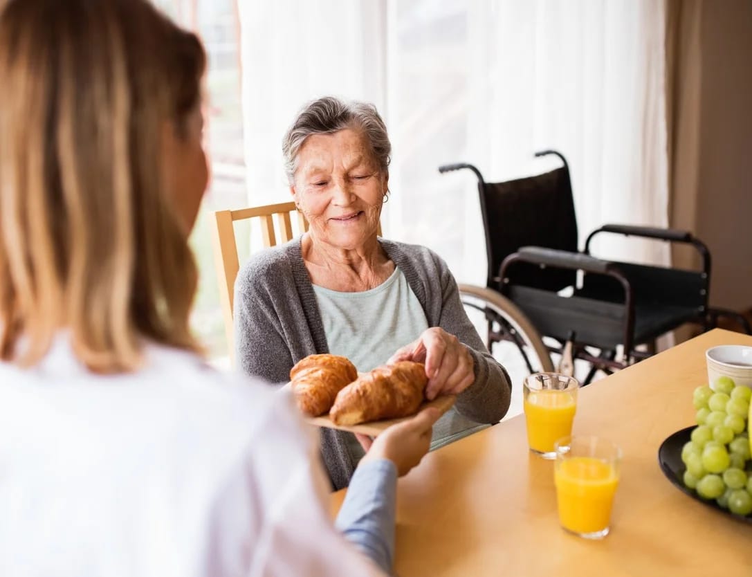 Caregiver serving food to a senior resident