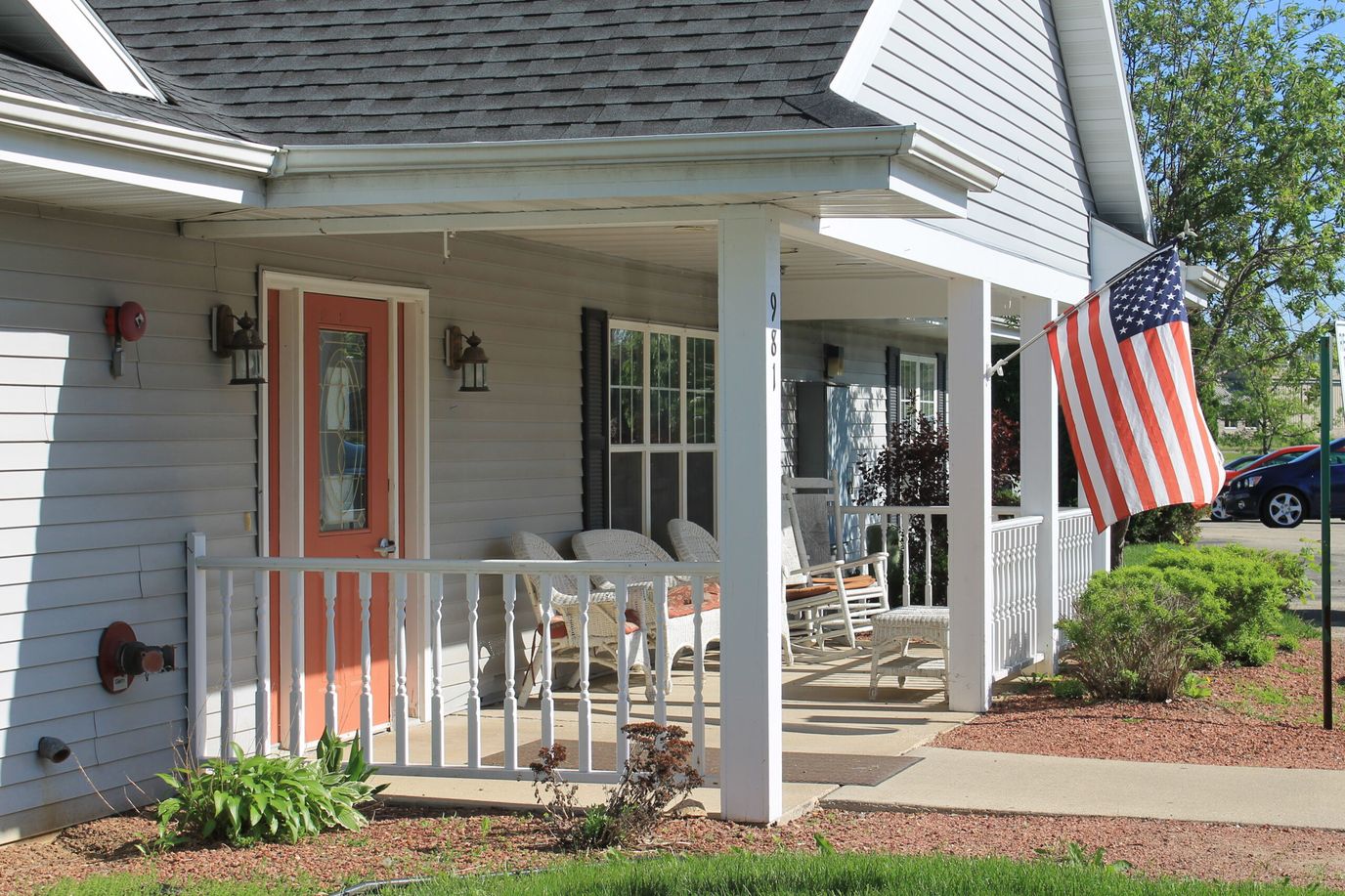 Exterior view of an assisted living facility with porch and flag