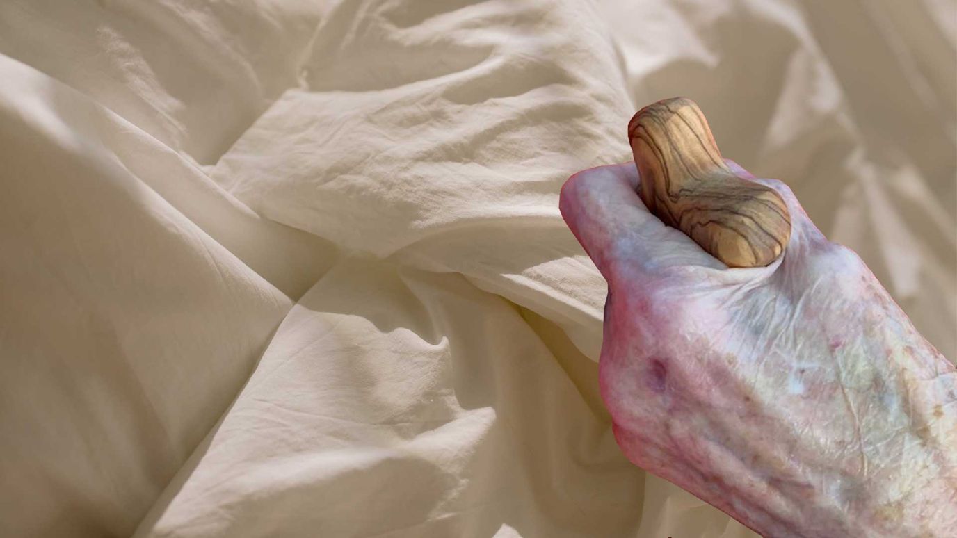 Close-up of an elderly person's hand gripping a cane.