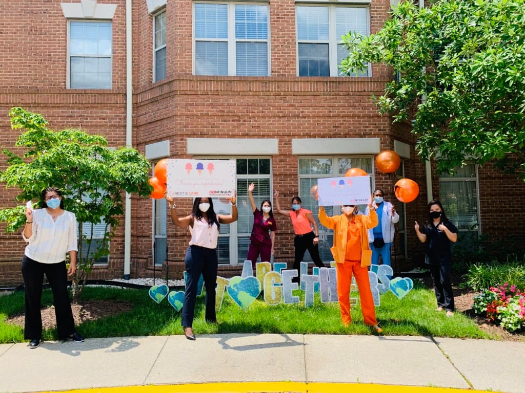 Staff celebrating in front of the facility with signs and balloons