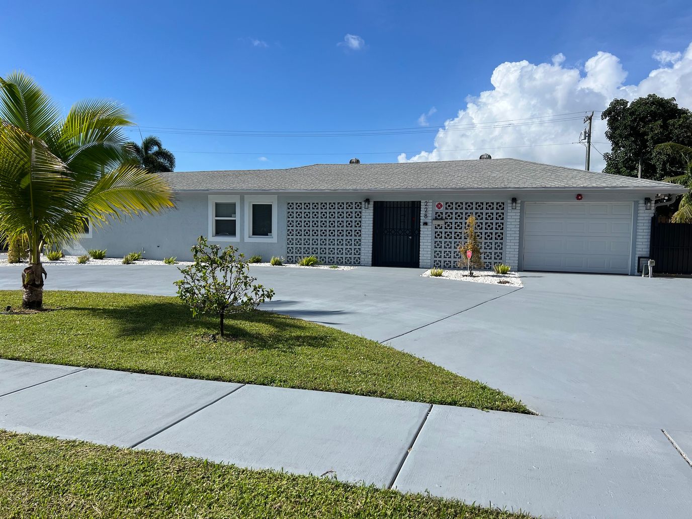 Exterior view of a residential care facility with a driveway and palm trees