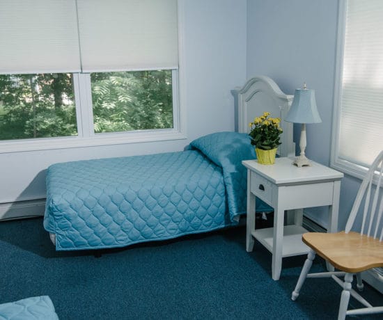 A private resident room with a bed and bedside table