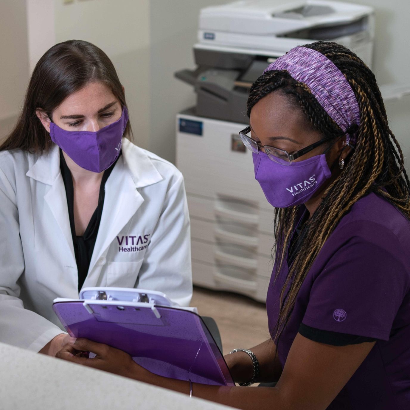 Two healthcare workers discussing patient information in an office setting.