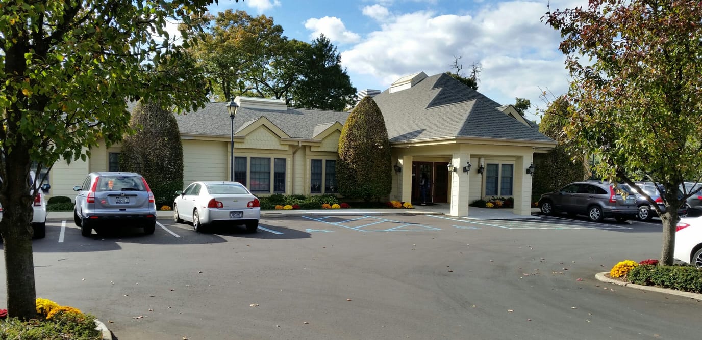 Exterior view of a senior living facility with cars parked