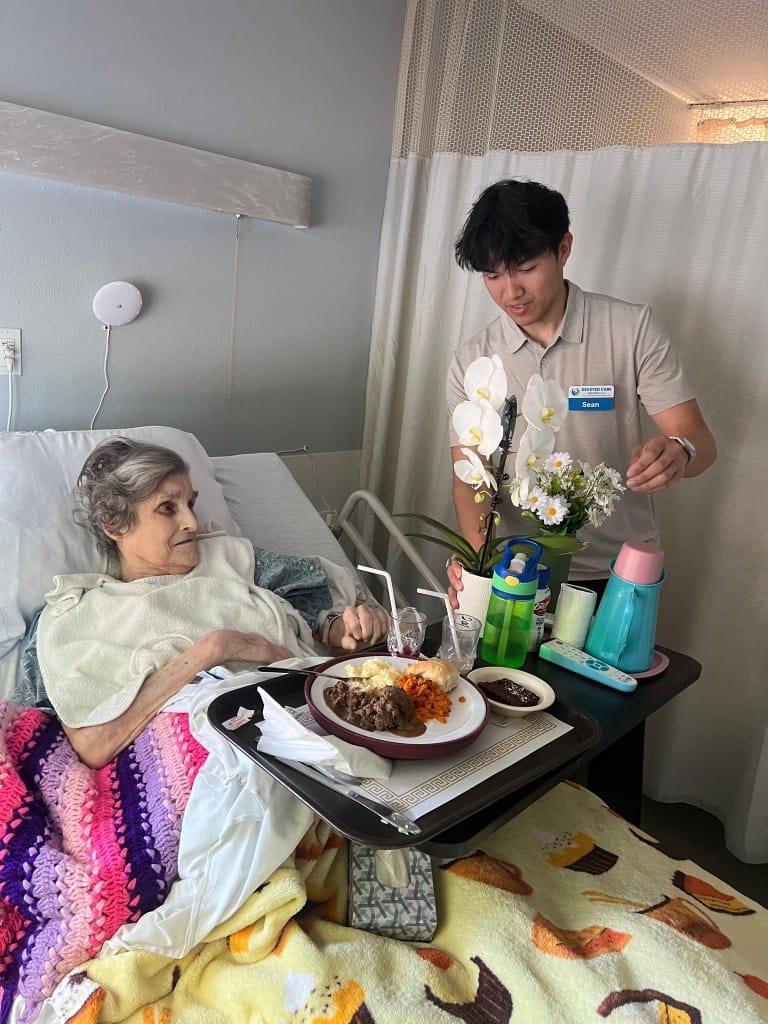 Staff assisting a resident with a meal in a room