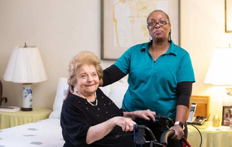Senior resident smiling with caregiver in a bright room