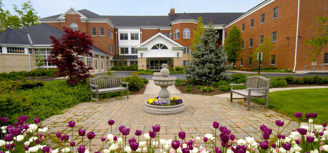 Exterior view of Beechwood Home with flower beds and benches