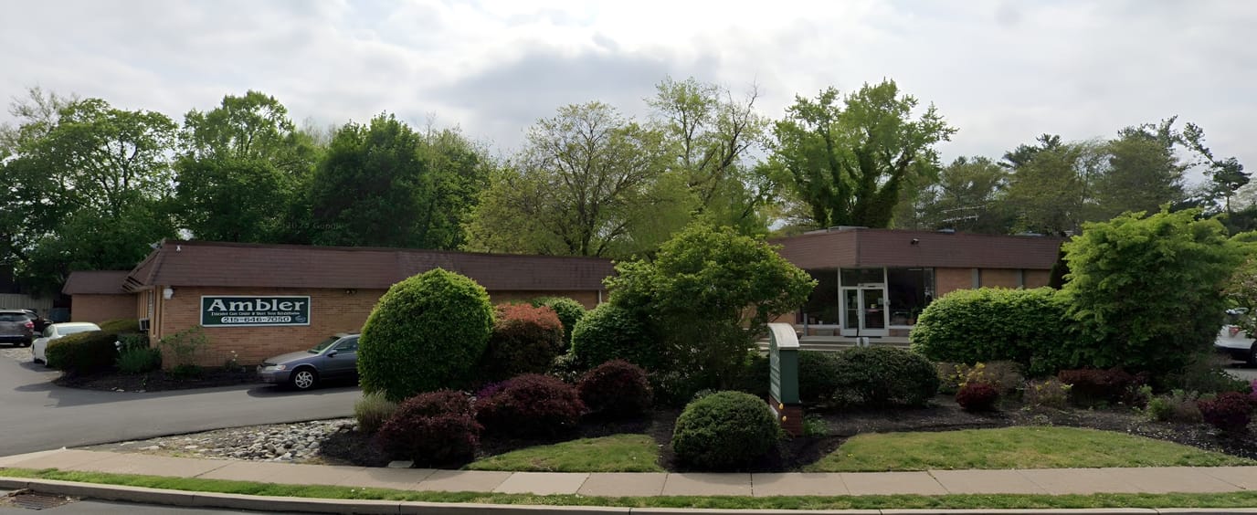Exterior view of Ambler Extended Care Center surrounded by greenery
