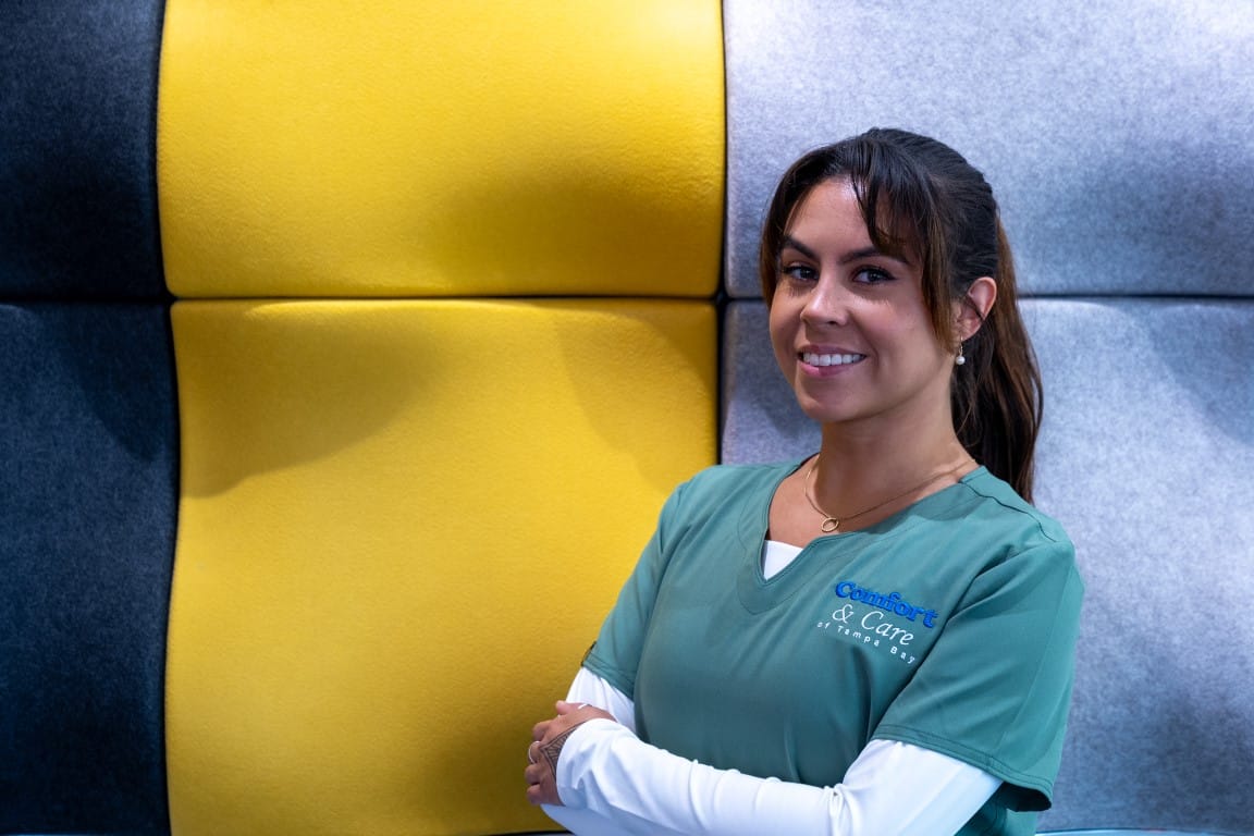 Staff member in a green uniform against a colorful background