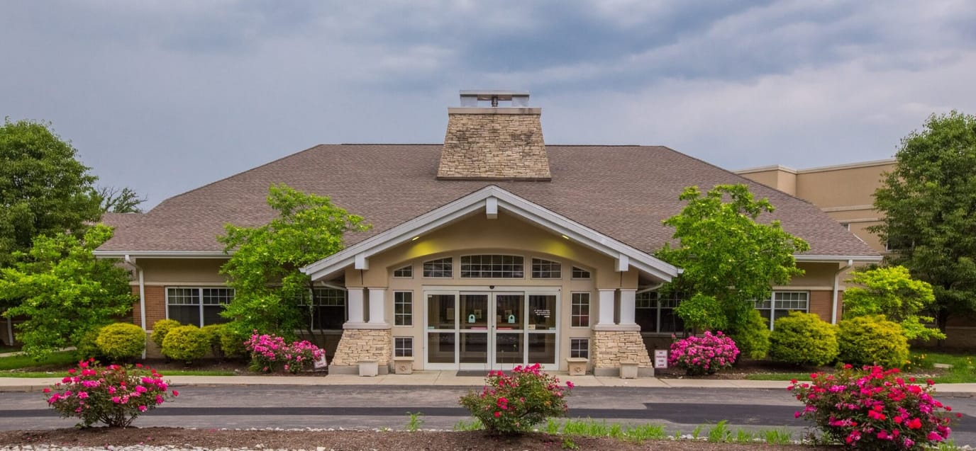 Exterior view of a senior living facility surrounded by flowers