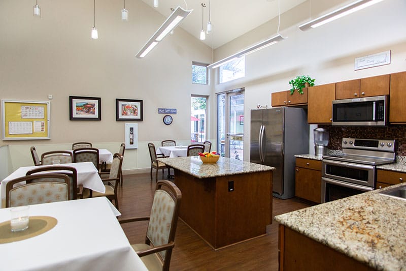 Interior view of a dining room with tables and kitchen area