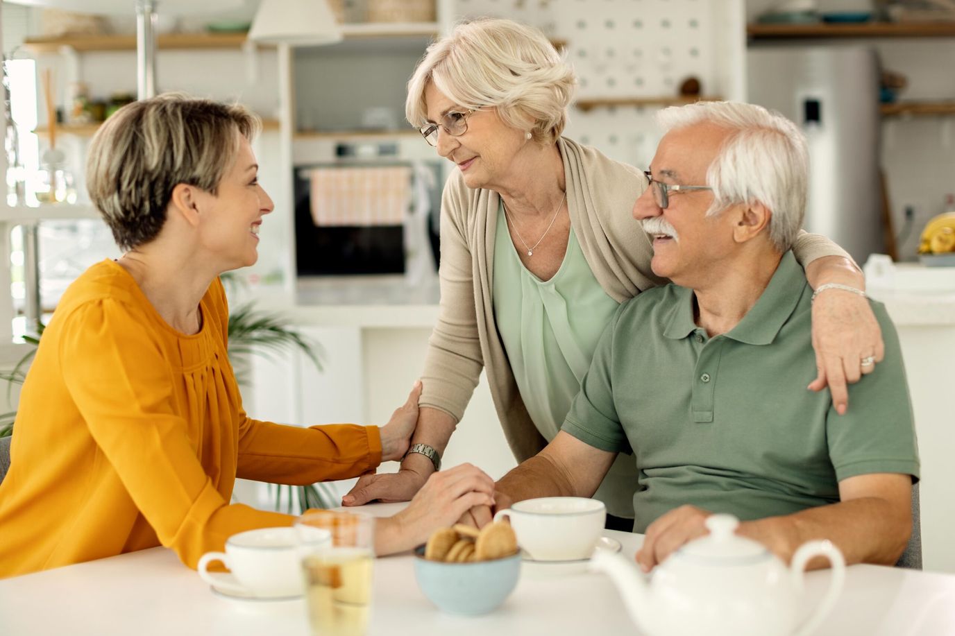 A caregiver interacting with two senior residents at a table
