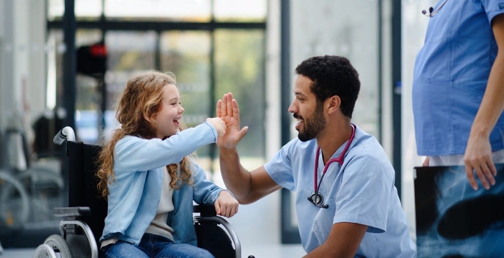 A caregiver and a child sharing a high-five in a facility hallway