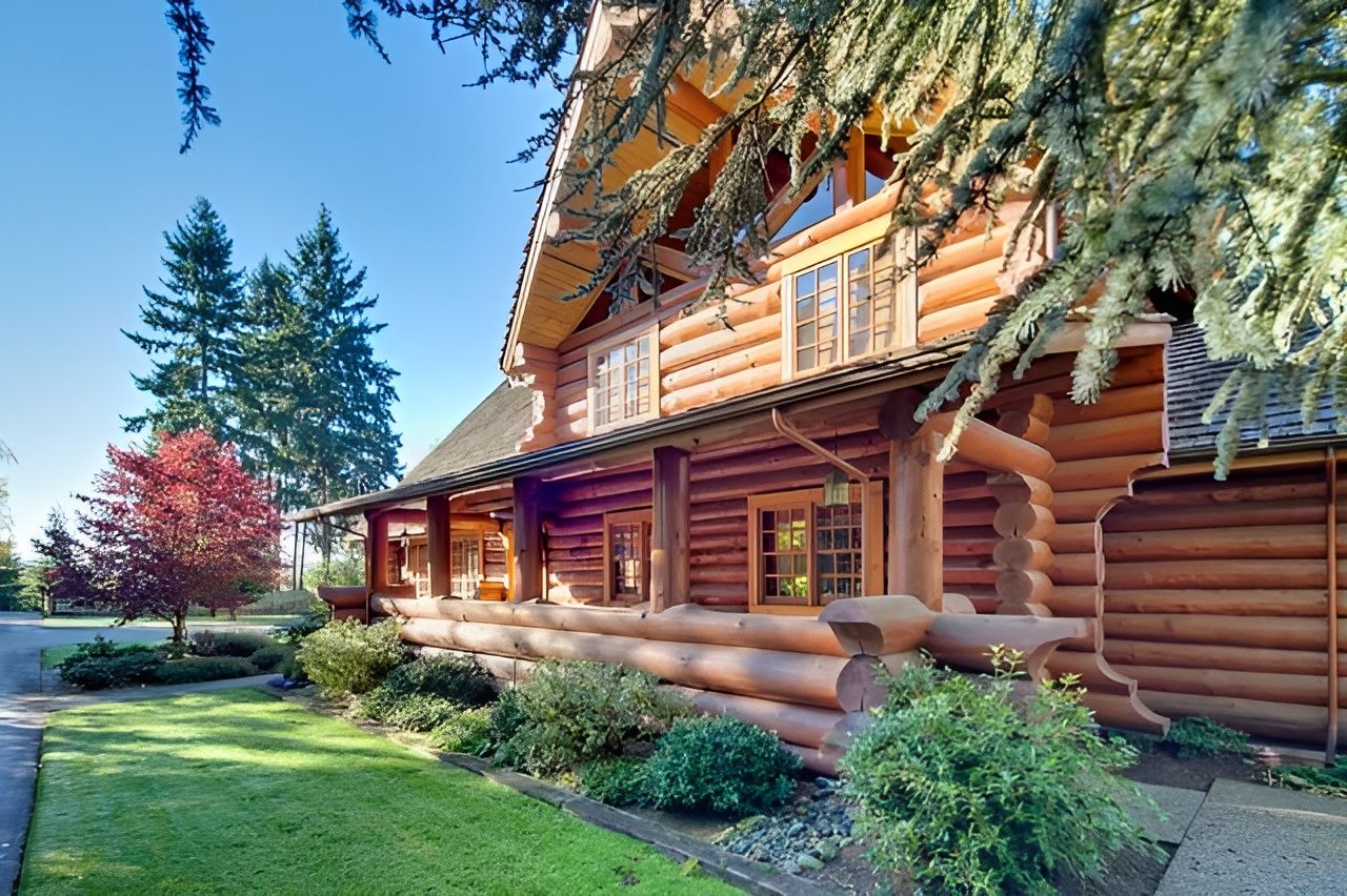 Exterior view of a large log cabin with landscaped grounds