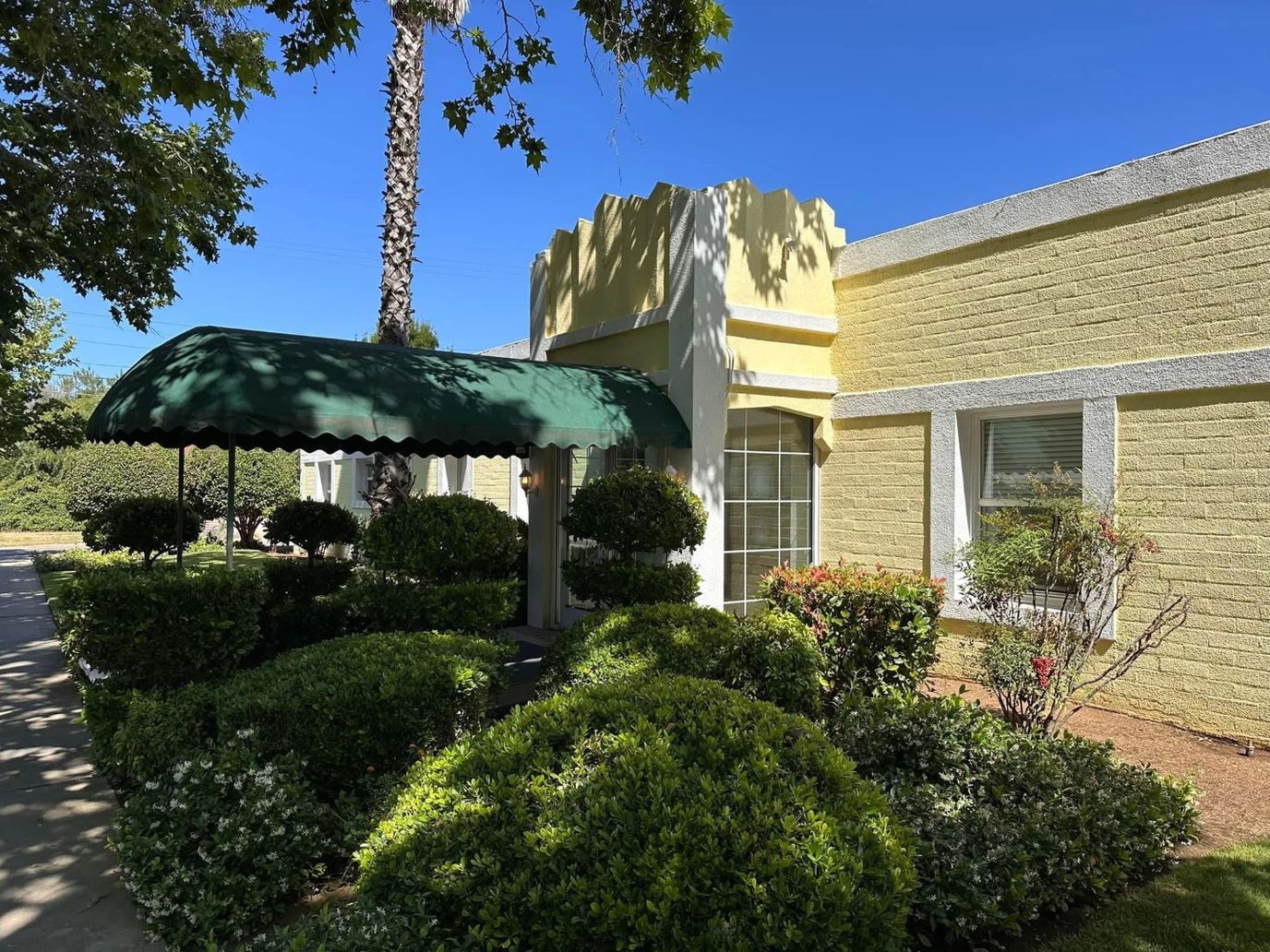 Front entrance of a facility with garden and awning