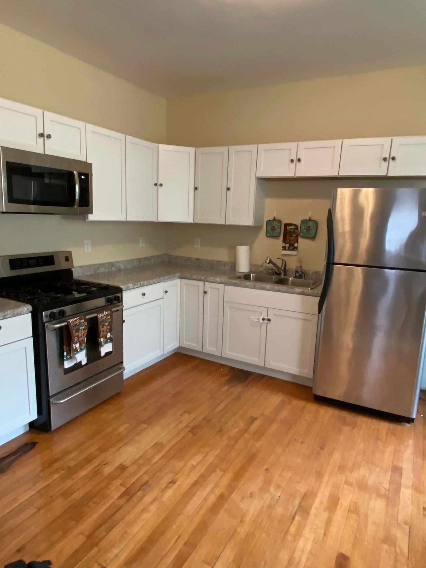Bright kitchen area with appliances and wood flooring
