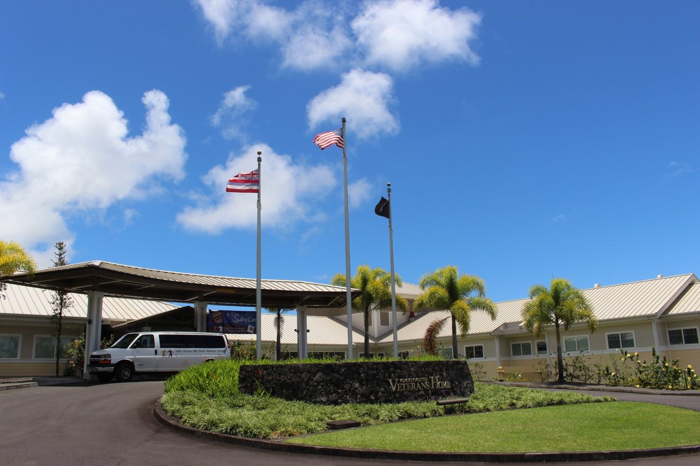 Entrance of Yukio Okutsu State Veterans Home with flags and vehicle