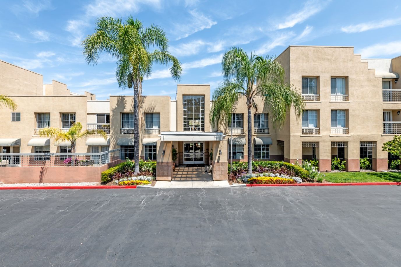 Front exterior of Park Plaza facility with palm trees and flowers