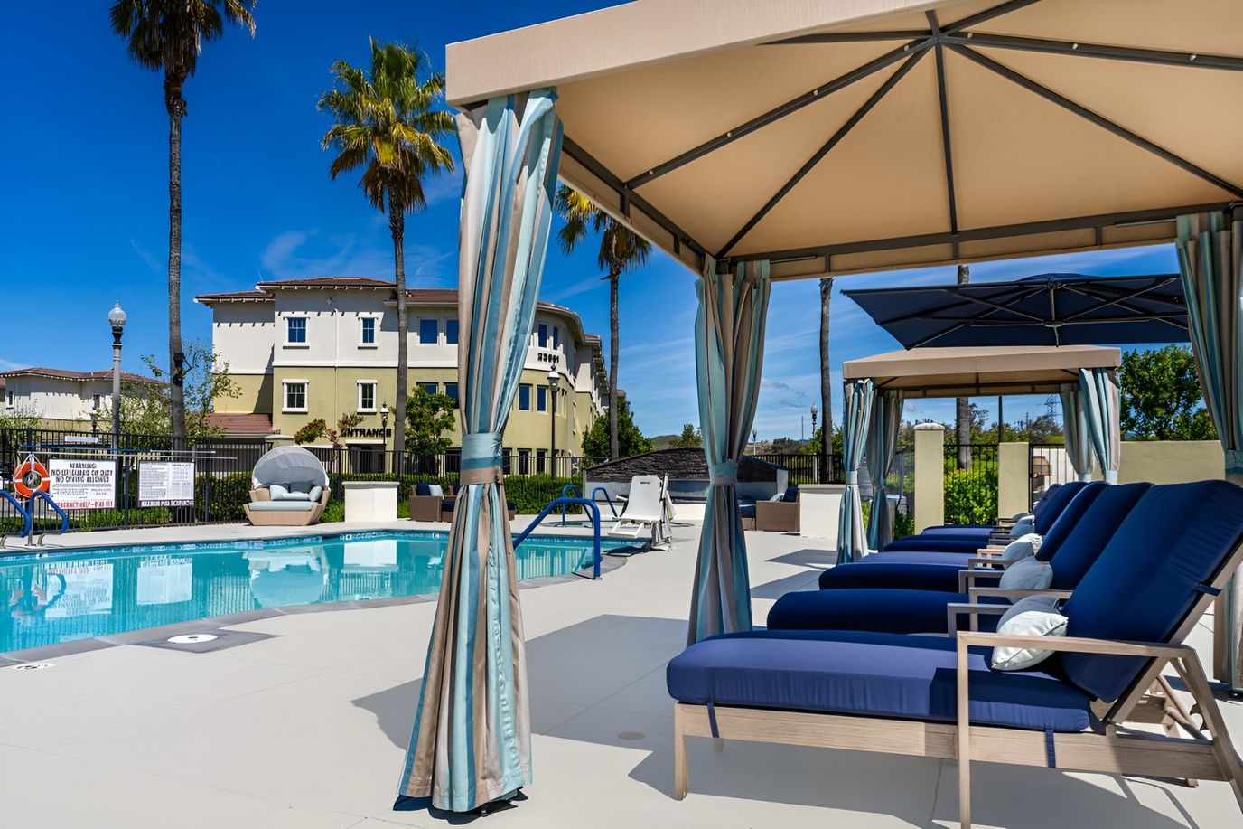Outdoor pool area with lounge chairs and cabanas