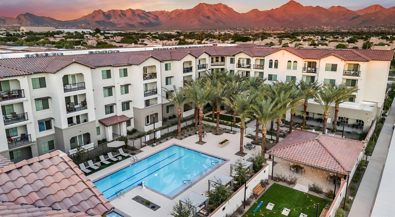 Aerial view of a senior living facility with a pool and palm trees