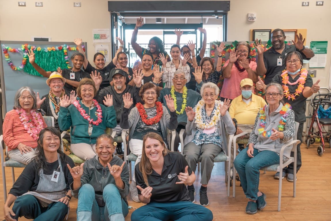 Residents and staff joyfully posing in a common area