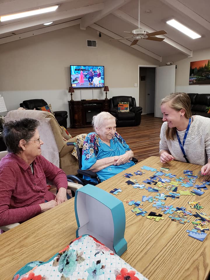 Residents playing a puzzle game with staff in a common area