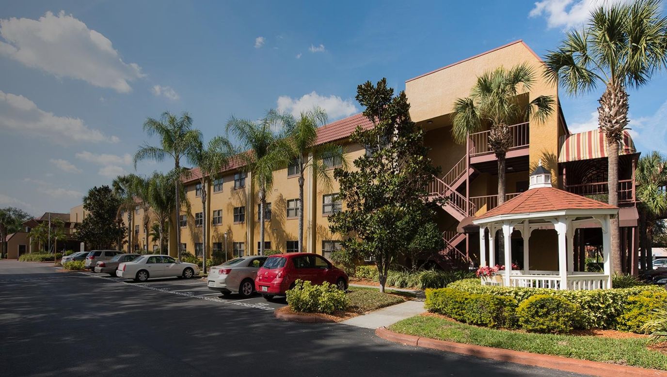 Exterior view of a senior living facility with palm trees