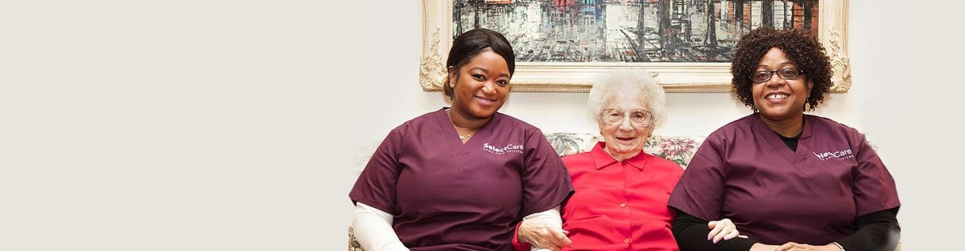 Two caregivers sitting with a resident in a cozy setting.