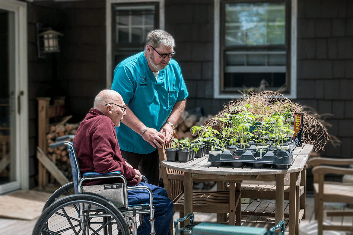 Senior resident gardening with staff assistance.