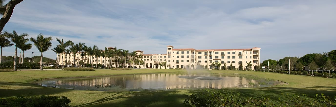 Exterior view of a senior living facility with garden and pond