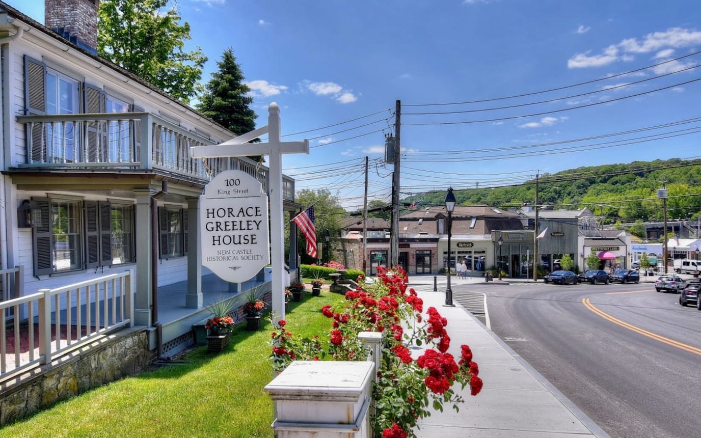 Exterior view of Horace Greeley House with flowers and signage