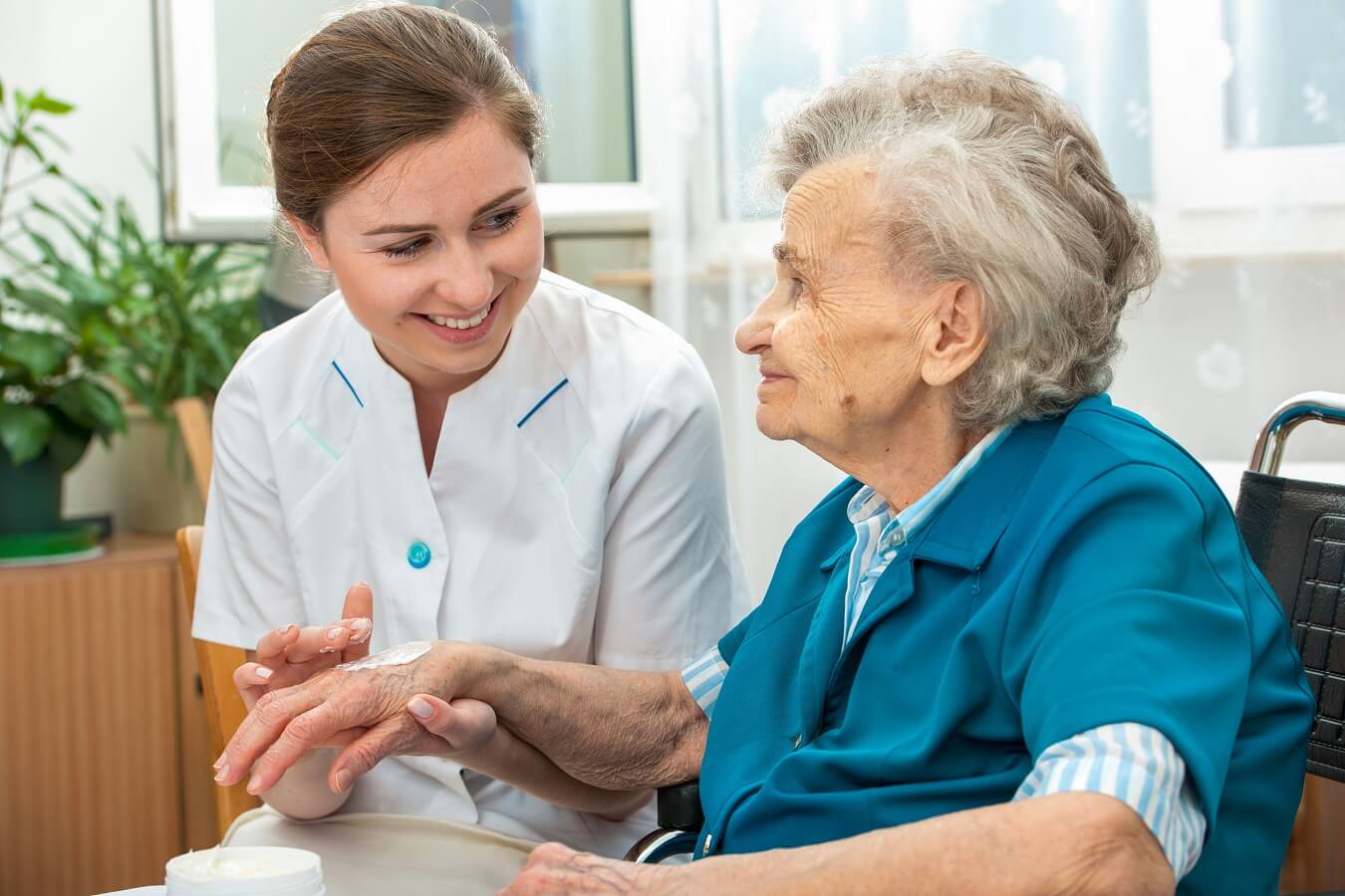 Caregiver assisting an elderly resident in a bright room