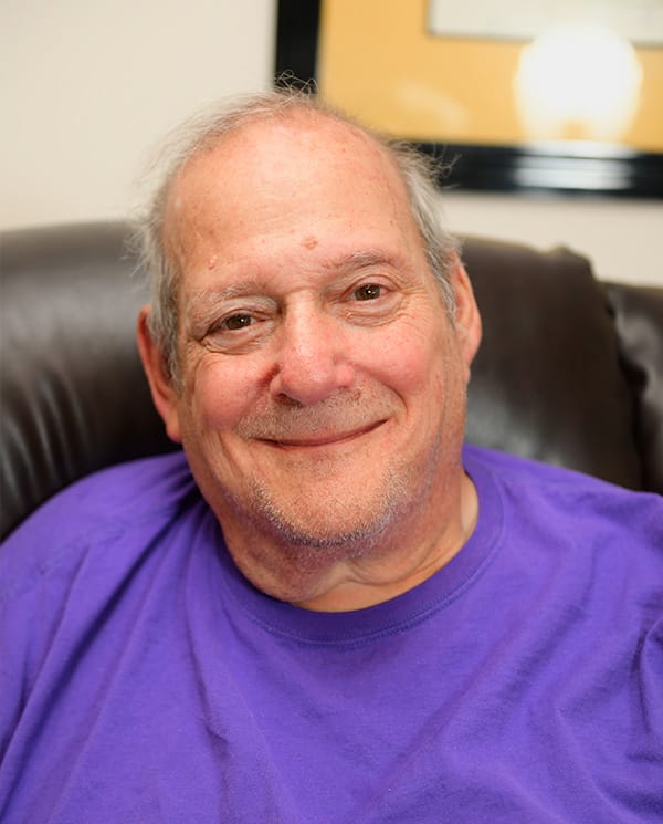 A smiling resident in a purple shirt