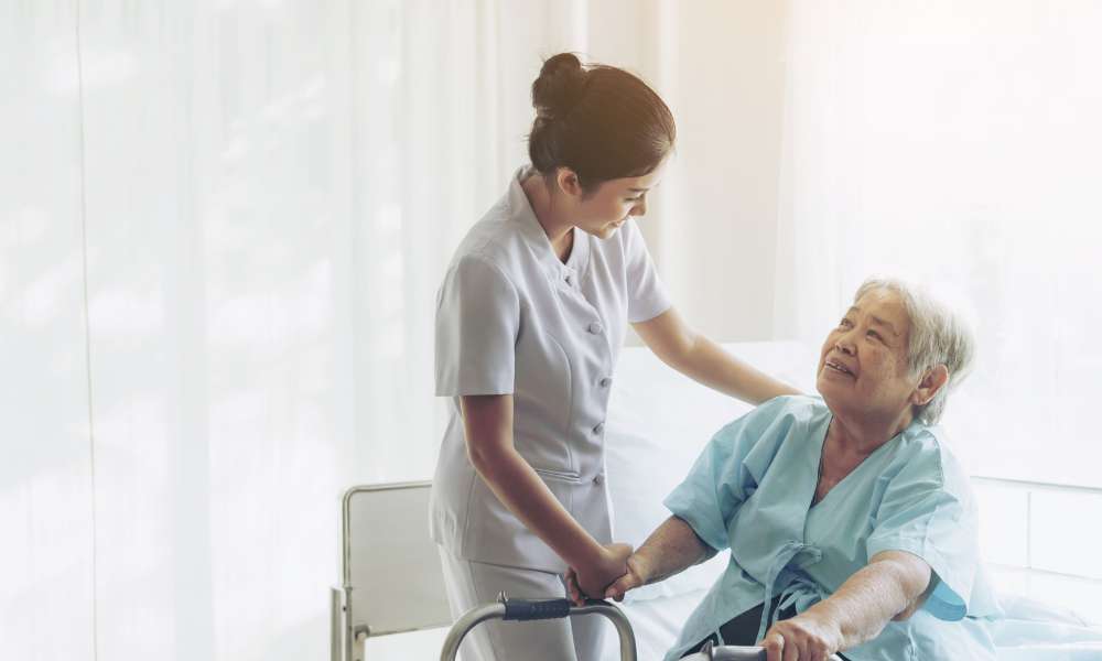 A caregiver assisting an elderly woman in a room.