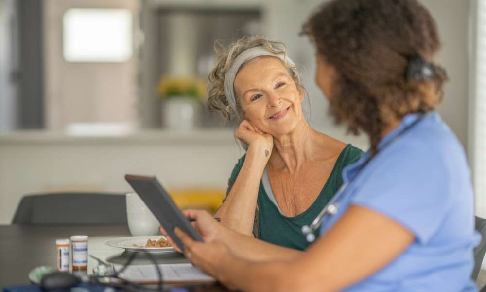 A caregiver and a smiling resident at the dining table