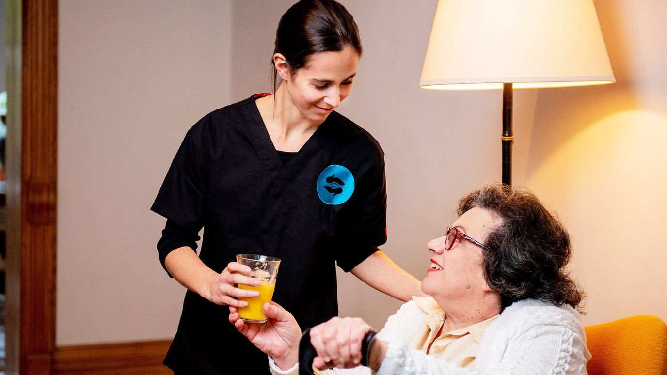 Staff member assisting a resident with a drink.