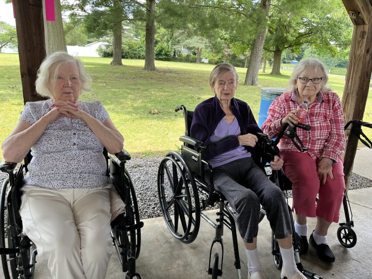 Three residents enjoying time outside in wheelchairs